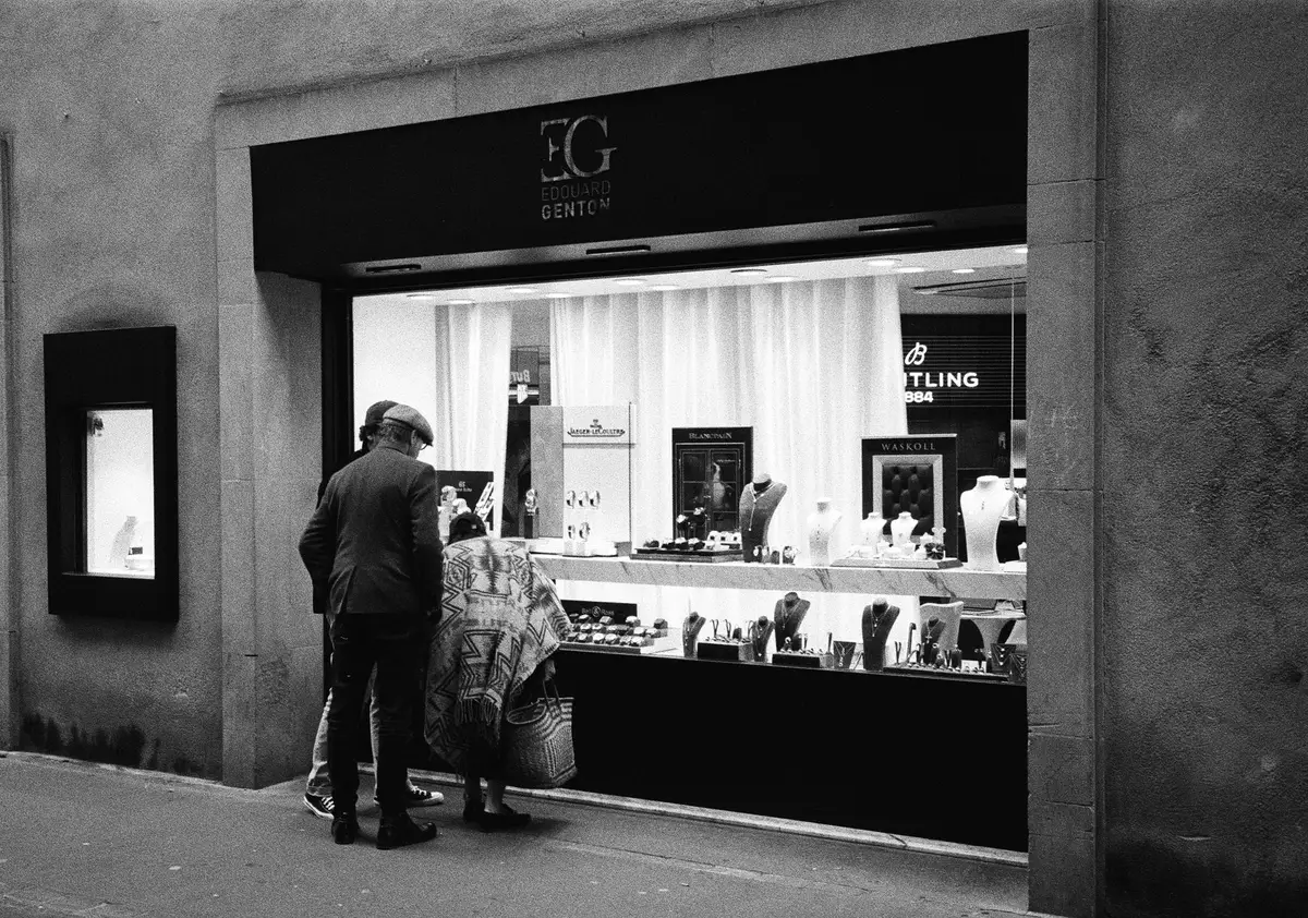 A dramatic confrontation scene in a luxury jewelry showroom, with tension visible in body language and facial expressions, dimly lit with dramatic shadows