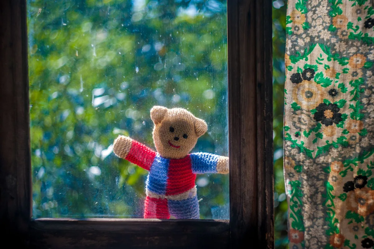An old doll lying on a wooden surface in soft light, a symbol of childhood innocence and abandonment, dust particles floating around it, the object of revelation