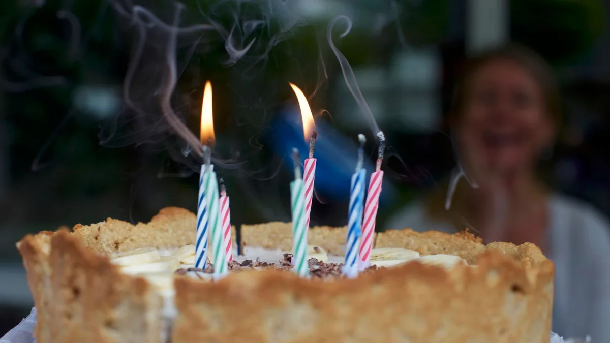 A vocalist in his 40s celebrating a milestone birthday, surrounded by nostalgic photographs from childhood to adulthood, with candles and warm lighting.