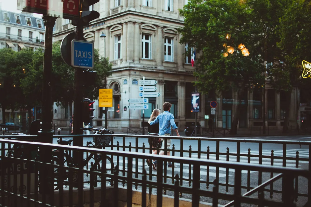 Couple silhouettes walking hand-in-hand through a romantic European cobblestone street at golden hour, warm sunset light, architecture blurred in background, intimate travel moment