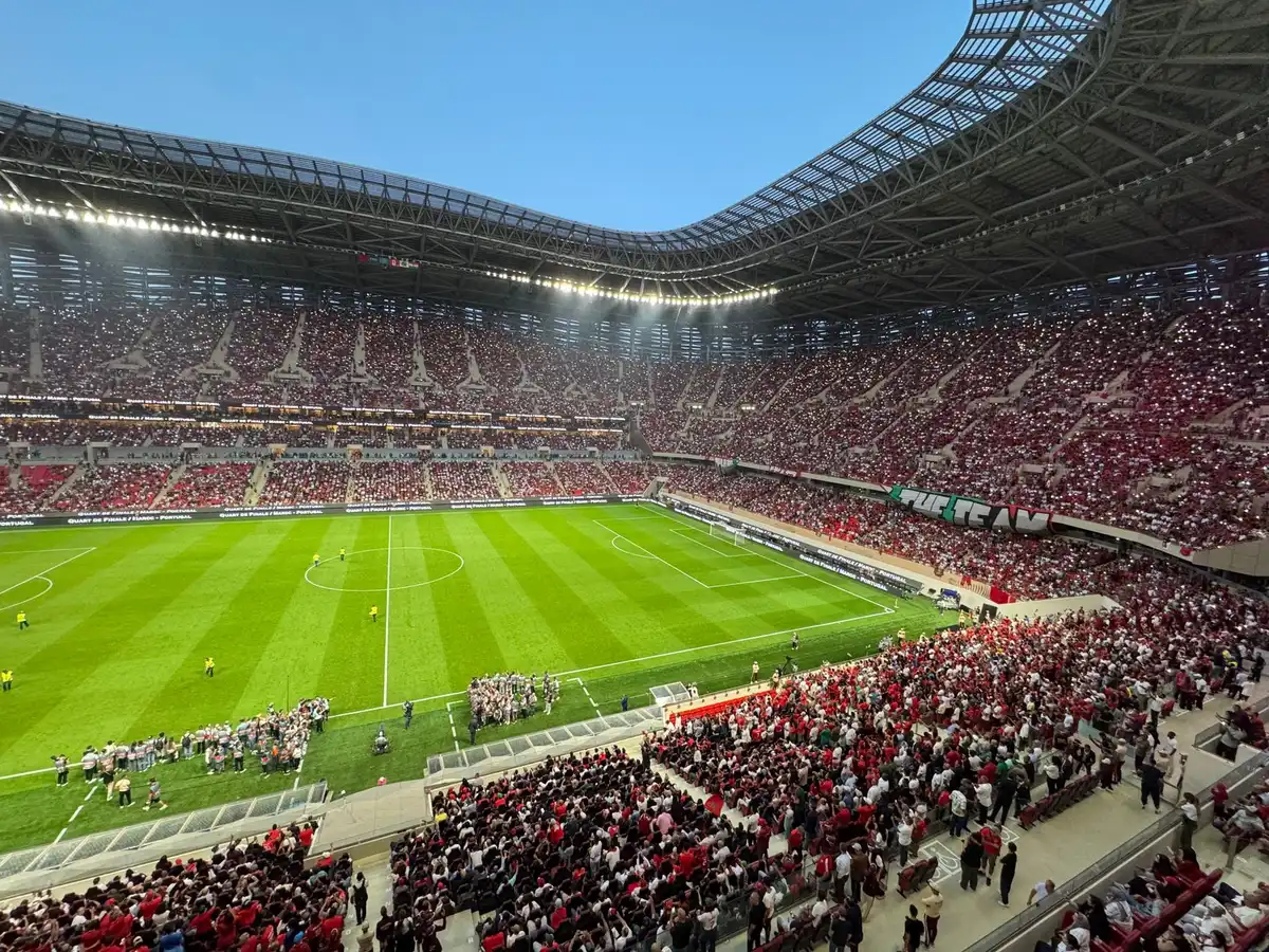 Estádio italiano com torcida animada, cores vibrantes, luzes do gramado refletindo em um dia de jogo da Serie A