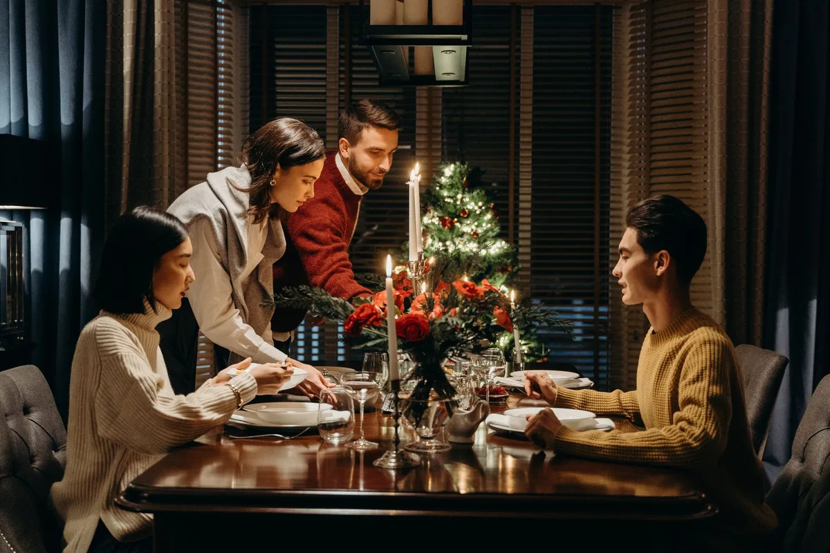 Family gathering scene with warm lighting, anonymous figures seated around a table, genuine smiles and relaxed postures suggesting approval and acceptance