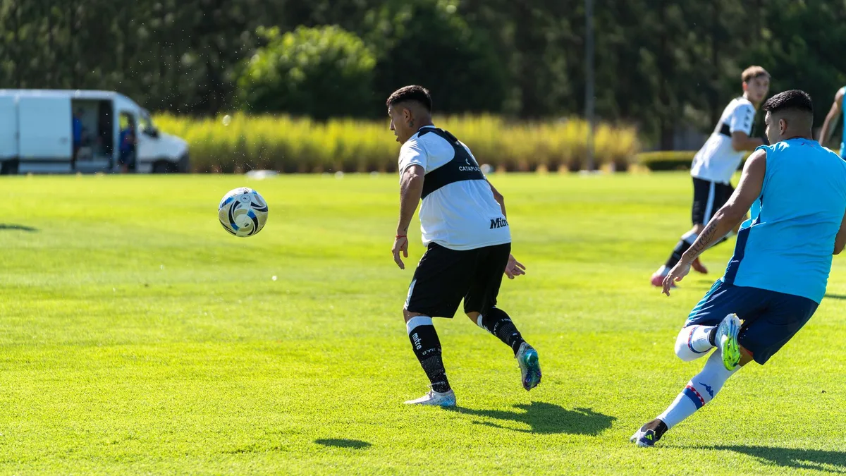 Young midfielder in yellow jersey making a precise pass across midfield, crowd blurred in background, stadium lights reflecting off the grass