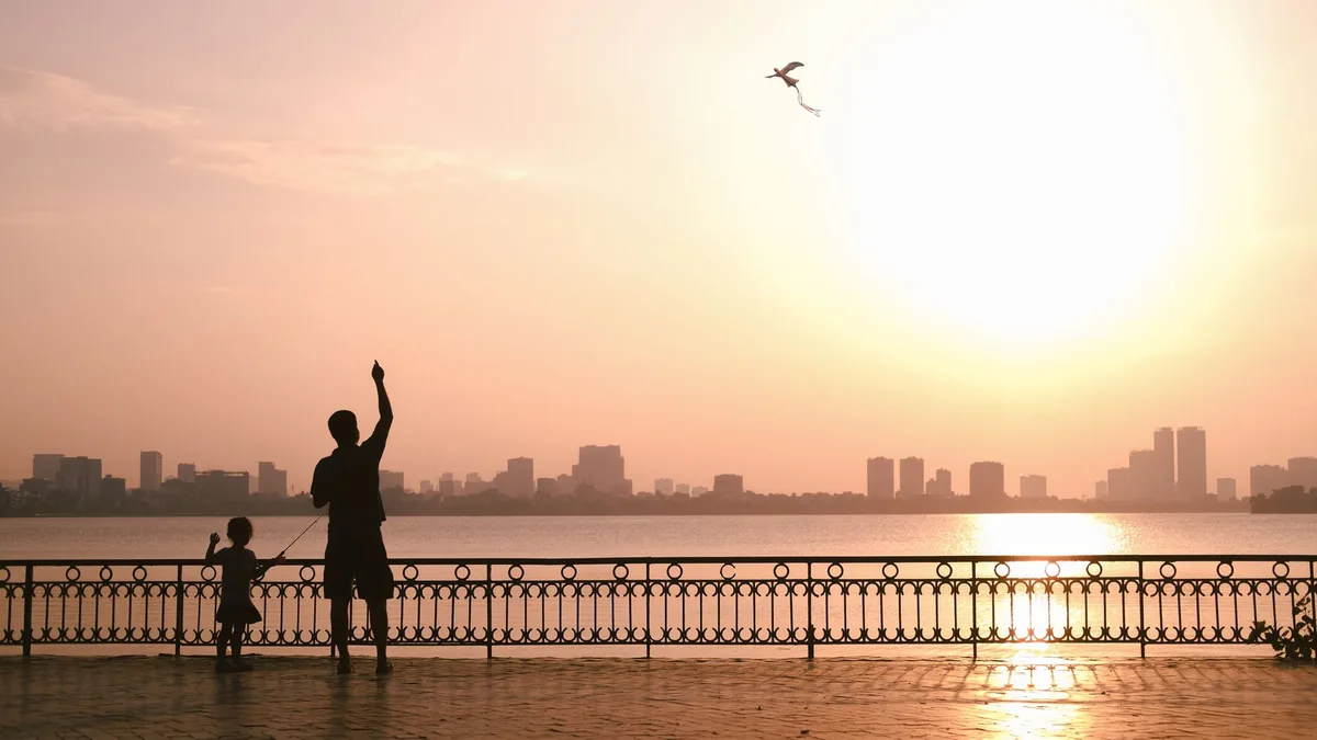 A family silhouette against golden sunset light, three small figures standing together, warm glow highlighting their outlines, a sense of connection and intimacy, soft haze in the background