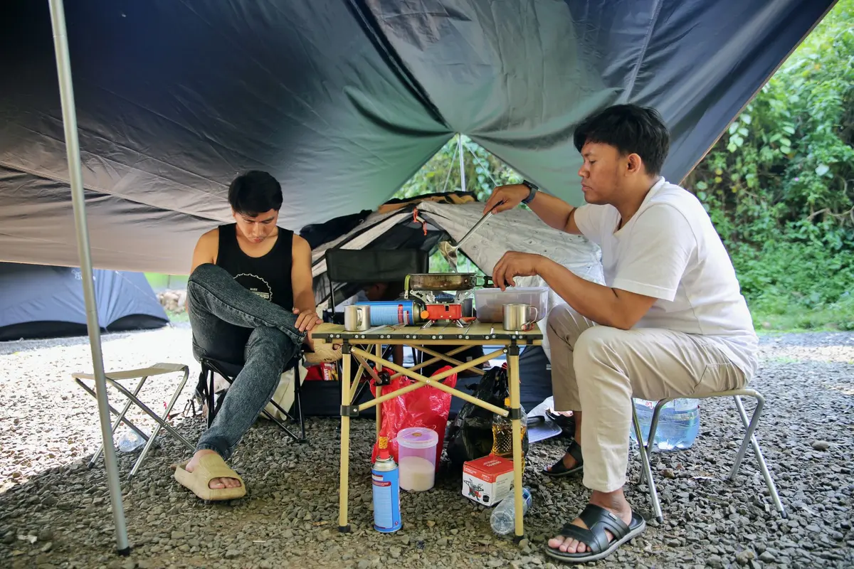 Camping area with new cabanas and facilities, visitors setting up tents and outdoor spaces, comfortable accommodation structures