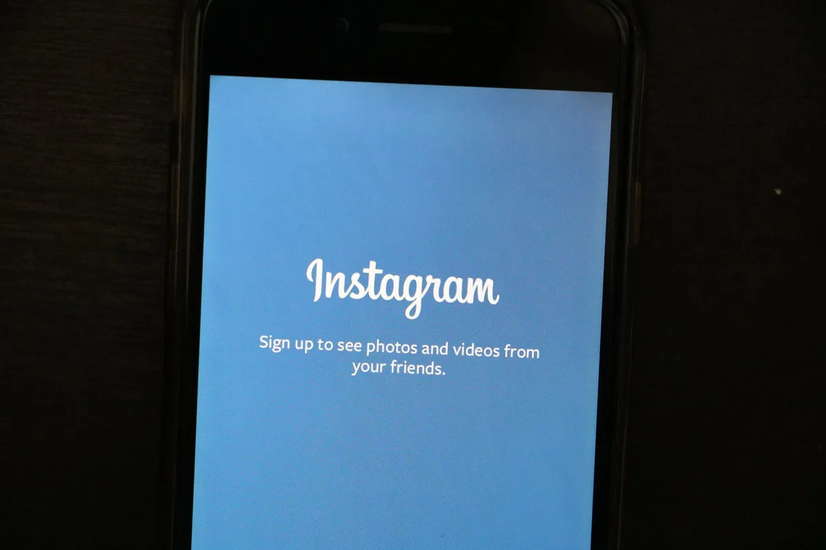 Deepfake warning alert on social media, anonymous figure viewing false promotional video on phone screen, digital manipulation concept