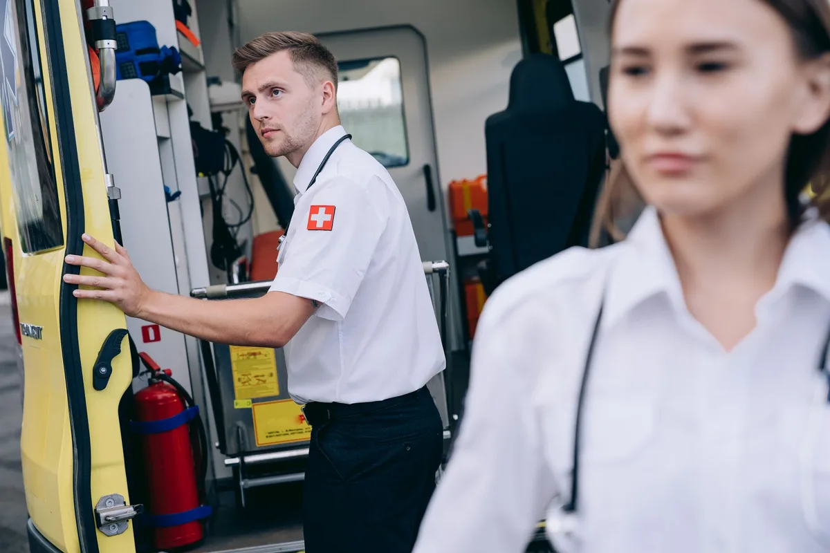 A medical emergency response unit in action, paramedics attending to a patient in an ambulance interior, intense focused expressions, equipment and monitors visible, dramatic lighting suggesting urgency.