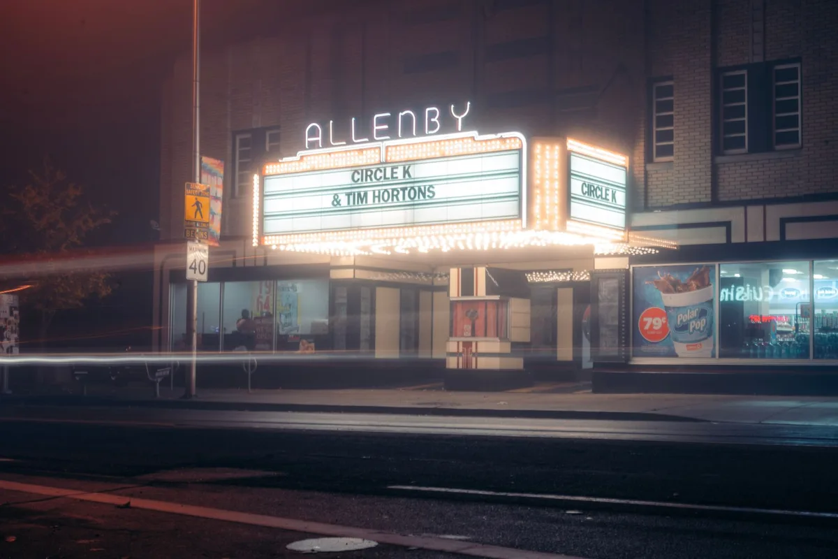 A glowing movie theater marquee displaying the Spider-Man film title in bold letters, with golden spotlights illuminating the entrance and excited silhouettes of moviegoers entering, capturing the theatrical excitement and record-breaking momentum.