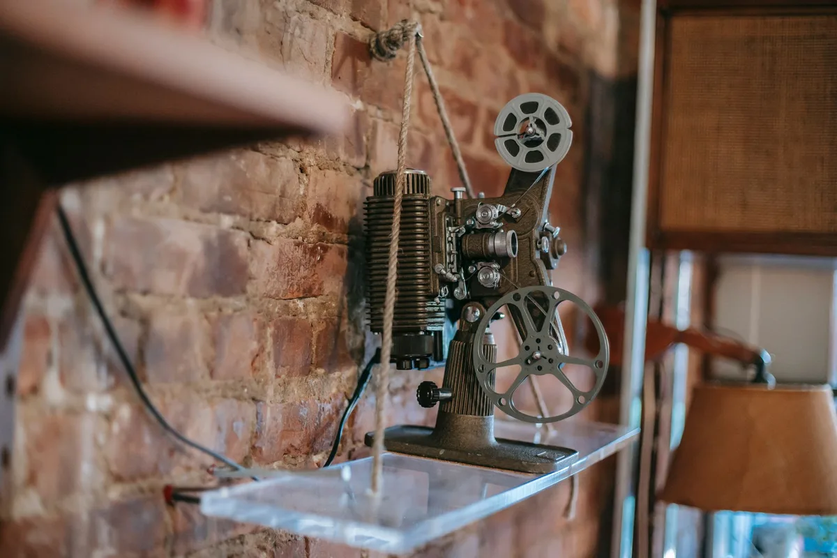 A split-screen comparison showing a vintage film projector on one side casting light onto a screen, and on the other side, a modern digital cinema projection system with vibrant colors, representing the evolution of cinema technology and the blockbuster era.
