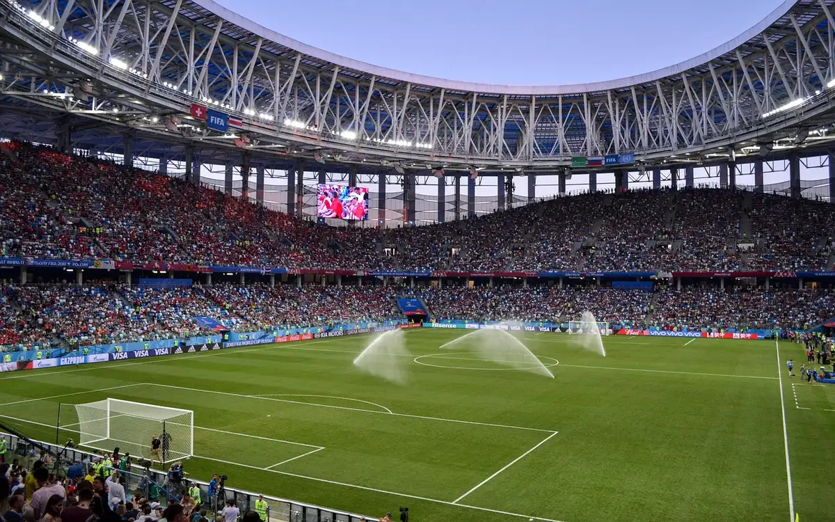 Empty stadium corridor with a single spotlight illuminating the field center, Inter crest visible on the pitch, evening shadows creeping across the turf, tension and anticipation