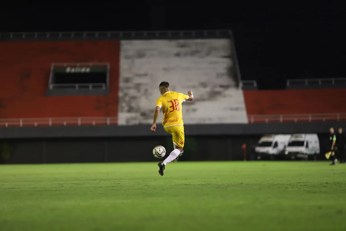 Stadium lights illuminating a packed arena, evening kickoff moment with fans in shadows, anticipation visible in the crowd's silhouettes