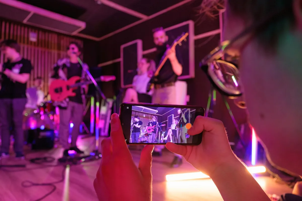 A modern music studio stage setup with two distinct color zones, one representing pop aesthetics with bright lights, another representing pagode with warm tones, microphones and instruments ready for group rehearsals