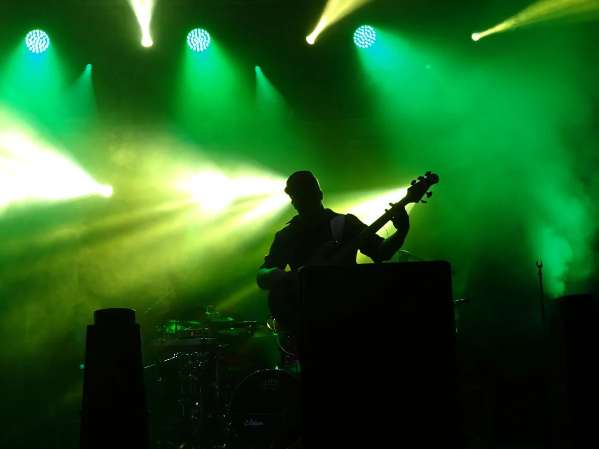 A concert venue interior with stage lighting and empty seats, suggesting the energy of live musical performance and group collaboration in a professional setting