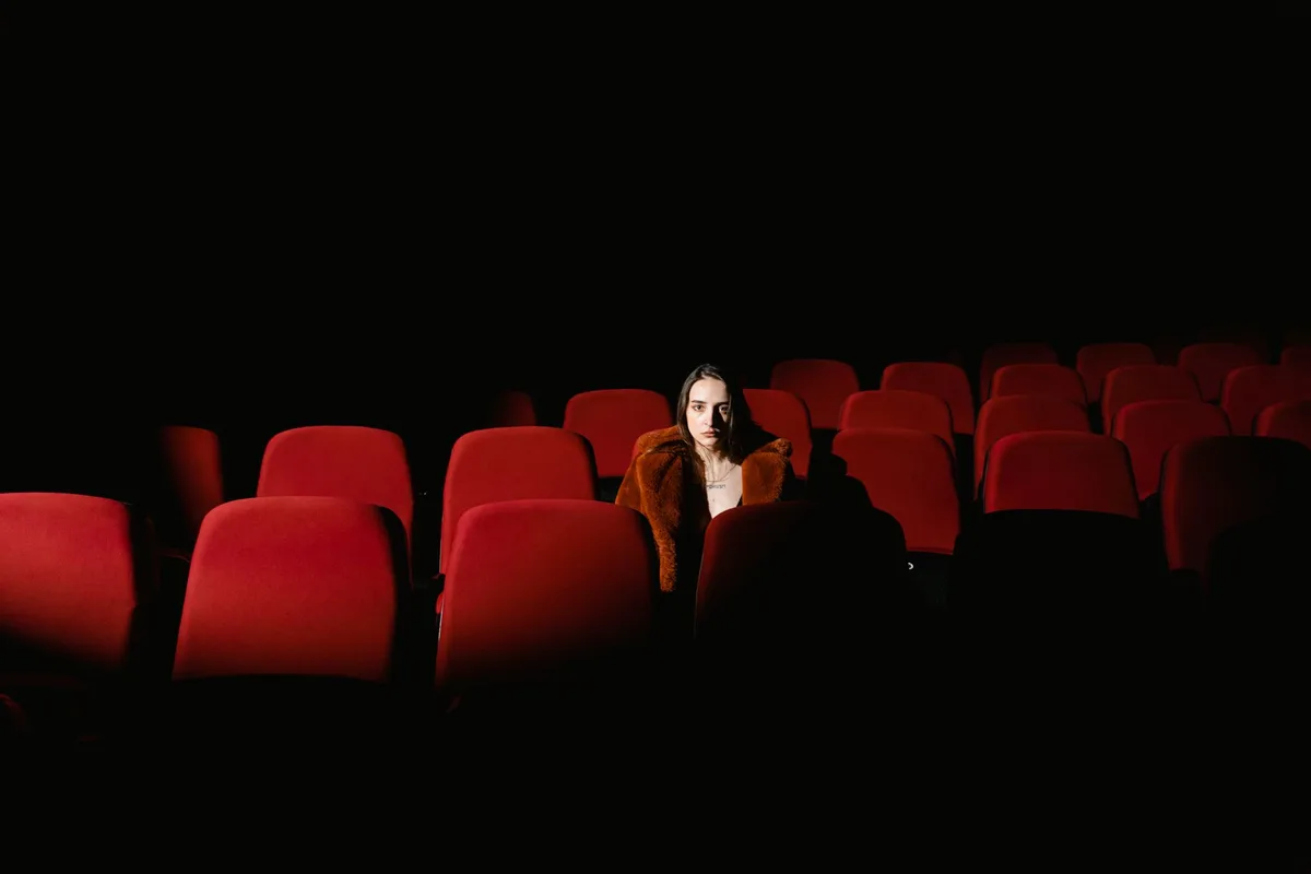 Two empty director's chairs facing each other on a dimly lit stage, a faded script page between them, theatrical lighting casting long shadows, suggesting decades of collaboration and shared artistry.