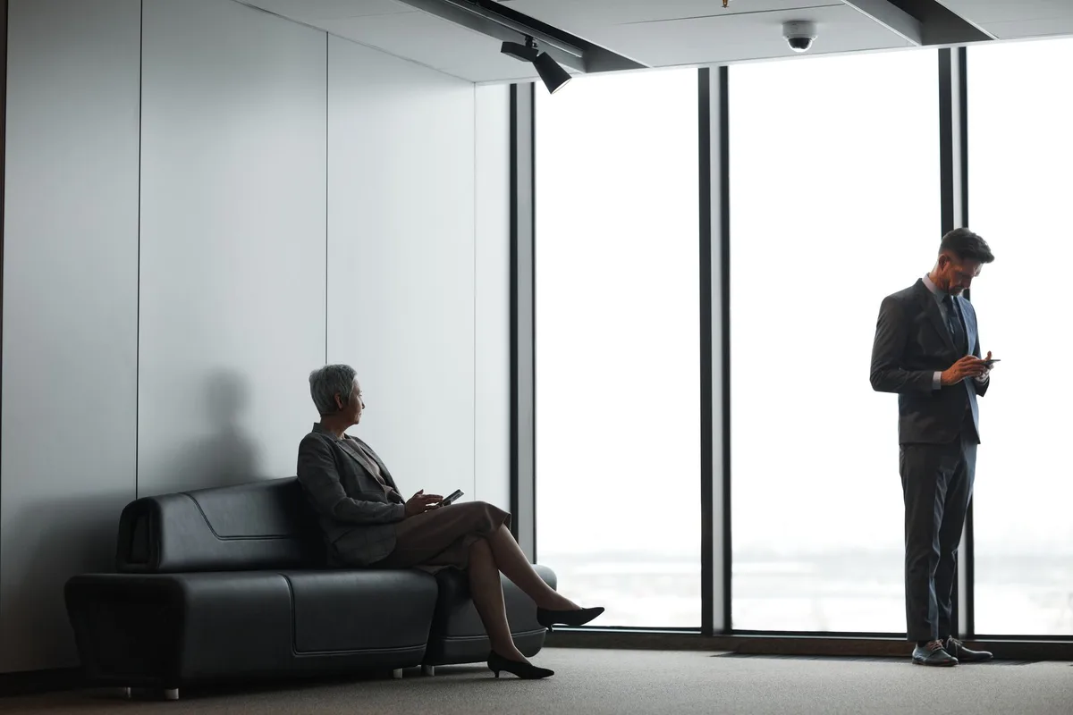 An empty executive office with a vacant chair at a polished desk, sunlight casting harsh shadows across the surface, papers scattered, a nameplate removed—suggesting a sudden loss of power and status