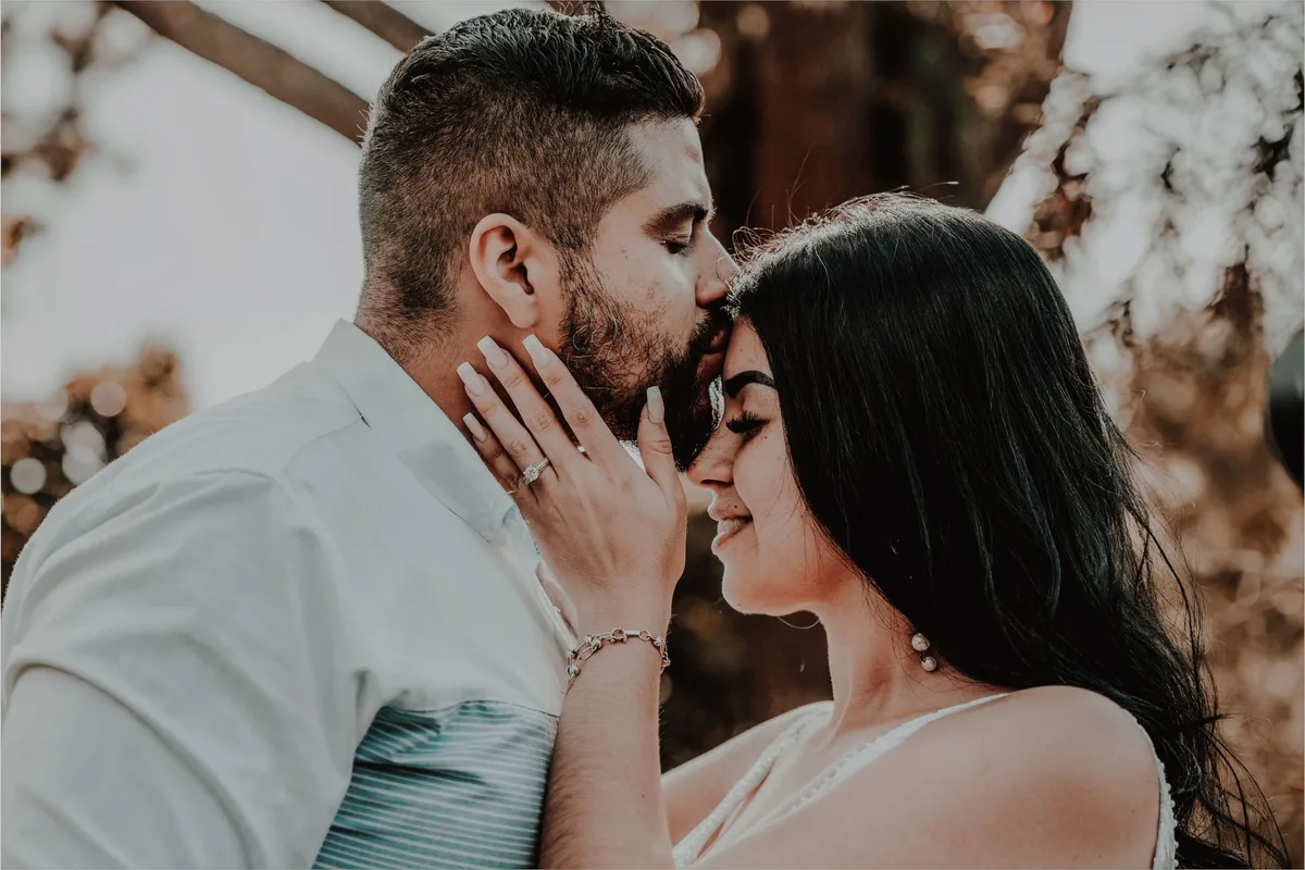Casal em momento íntimo, mostrando conexão e cumplicidade em ambiente aconchegante, com luz natural realçando expressões de carinho e proximidade