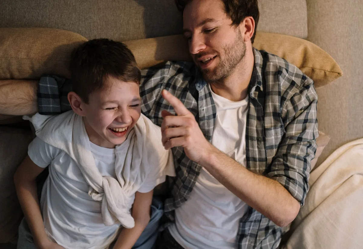 A father and son laughing together in casual conversation during an interview