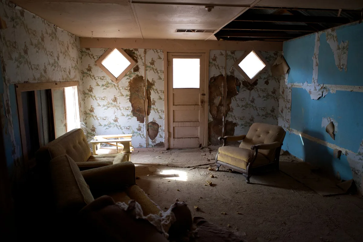 Empty nursery with soft afternoon light, a single chair by a window, stuffed animal on a shelf, gentle and serene atmosphere suggesting loss and remembrance