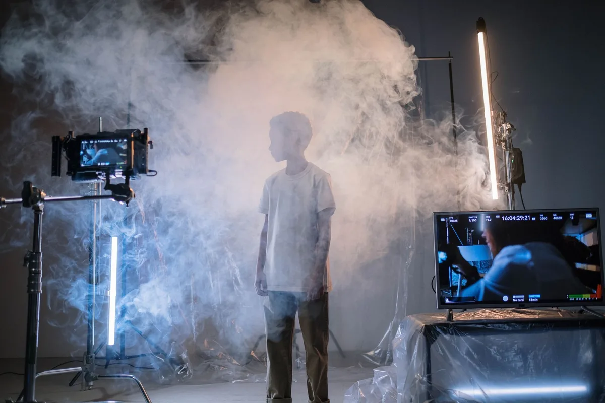 Film set or theater stage with dramatic lighting, spotlight on empty stage, professional cinema equipment visible, artistic atmosphere