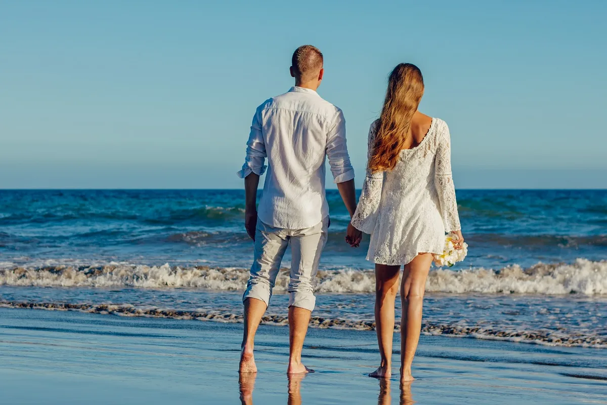 Couple silhouette at sunset on beach, waves in background, romantic moment, warm golden light, intimate and private