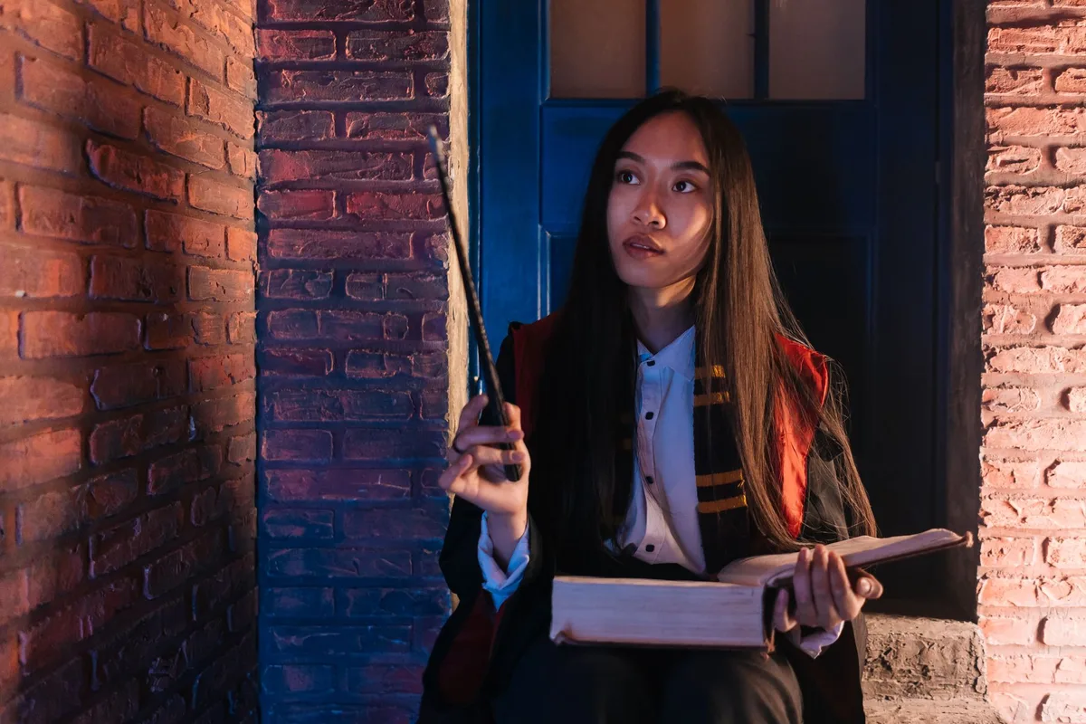 Ornate professor's desk with scattered magical books and a tarnished award for "Most Charming Smile," a name plate turned face-down, golden light filtering through gothic windows, theatrical and abandoned