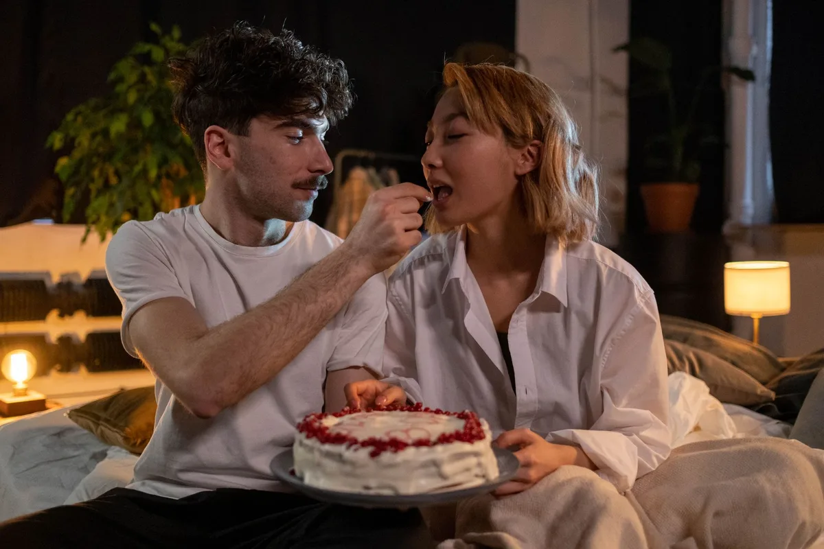 Anonymous couple in a rustic setting celebrating a shared birthday moment together, candlelight and warm emotion visible, intimate connection evident