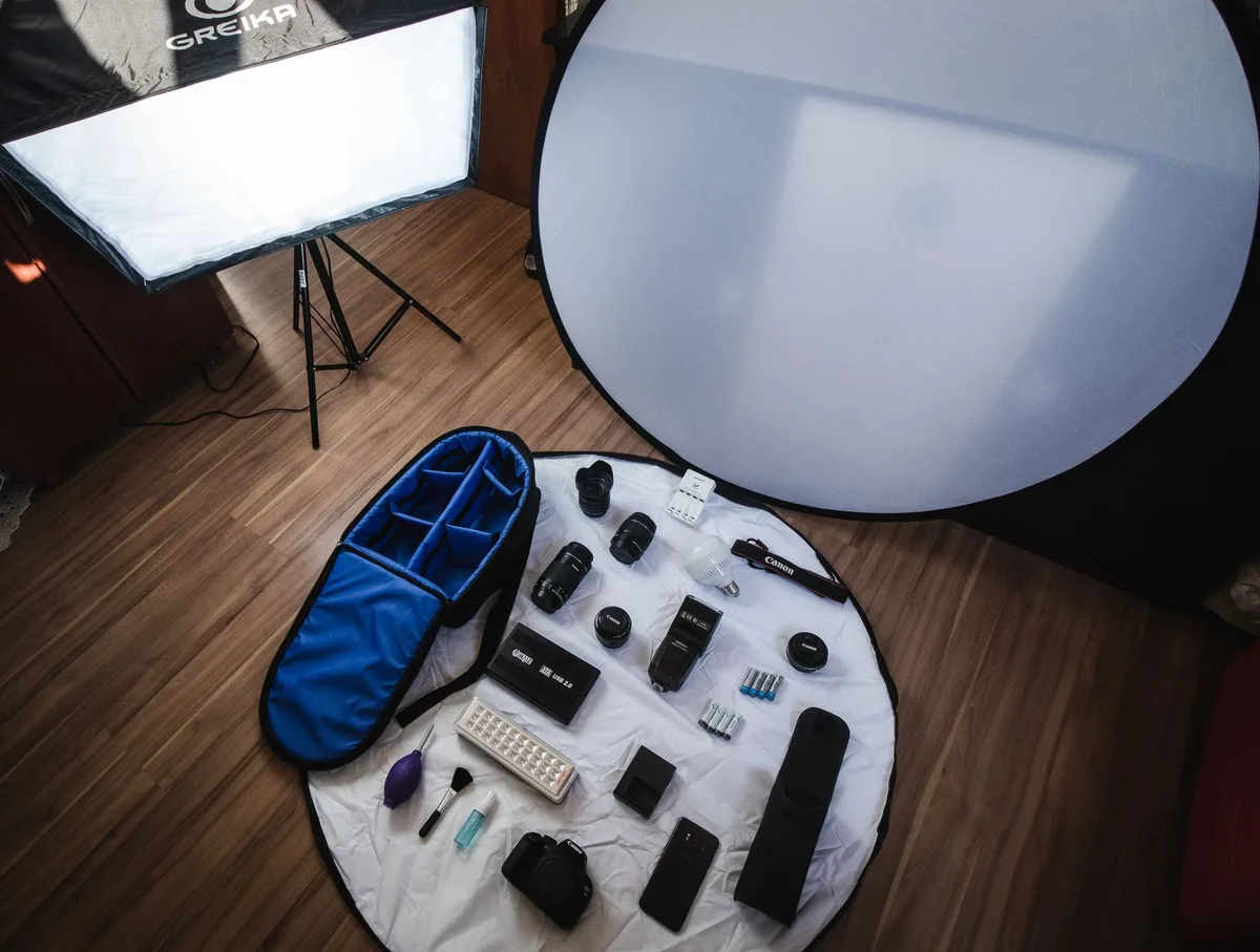 A modelo em estúdio fotográfico profissional, com iluminação de estúdio clássica, refletores e equipamento de câmera ao fundo desfocado, representando a indústria de fotografia de moda e ensaios.