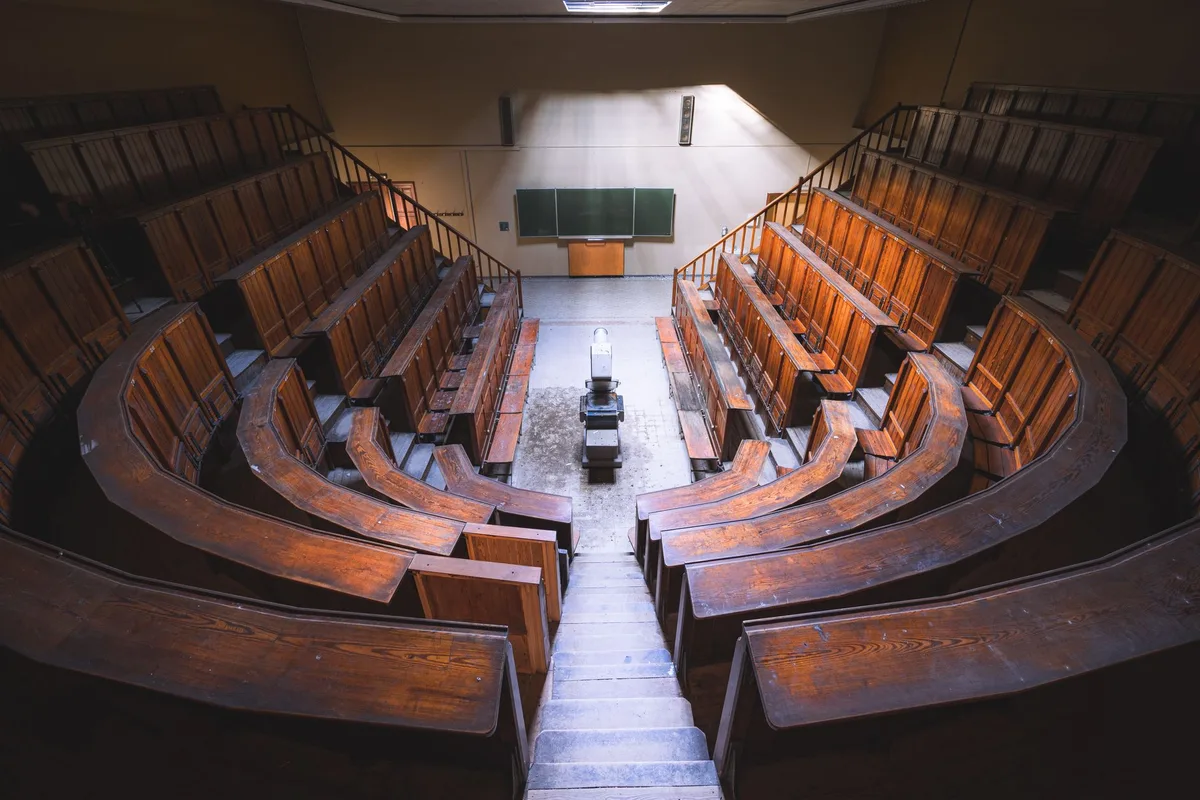 Um tribunal vazio com bancos de madeira, mesa do juiz ao fundo, luz natural entrando pelas janelas, representando o sistema de justiça.