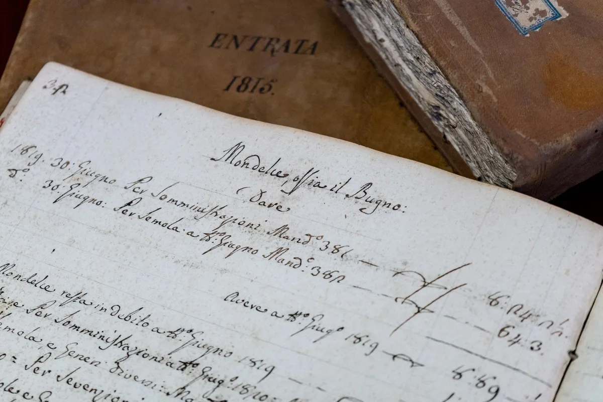Uma biblioteca ou arquivo com documentos antigos espalhados sobre uma mesa de madeira, representando o passado e histórias a serem descobertas