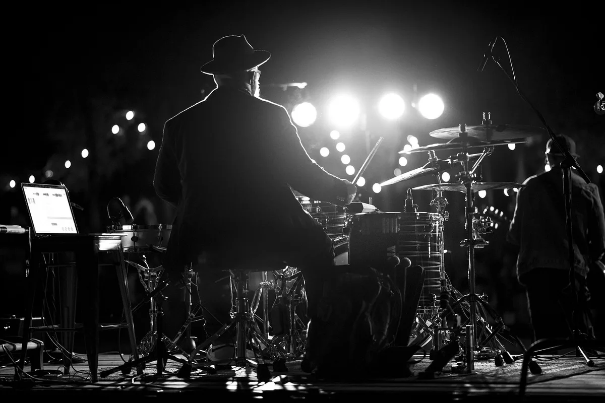 Concert stage with spotlight on solo female performer on horseback, arena packed with spectators, dust and emotion in the air