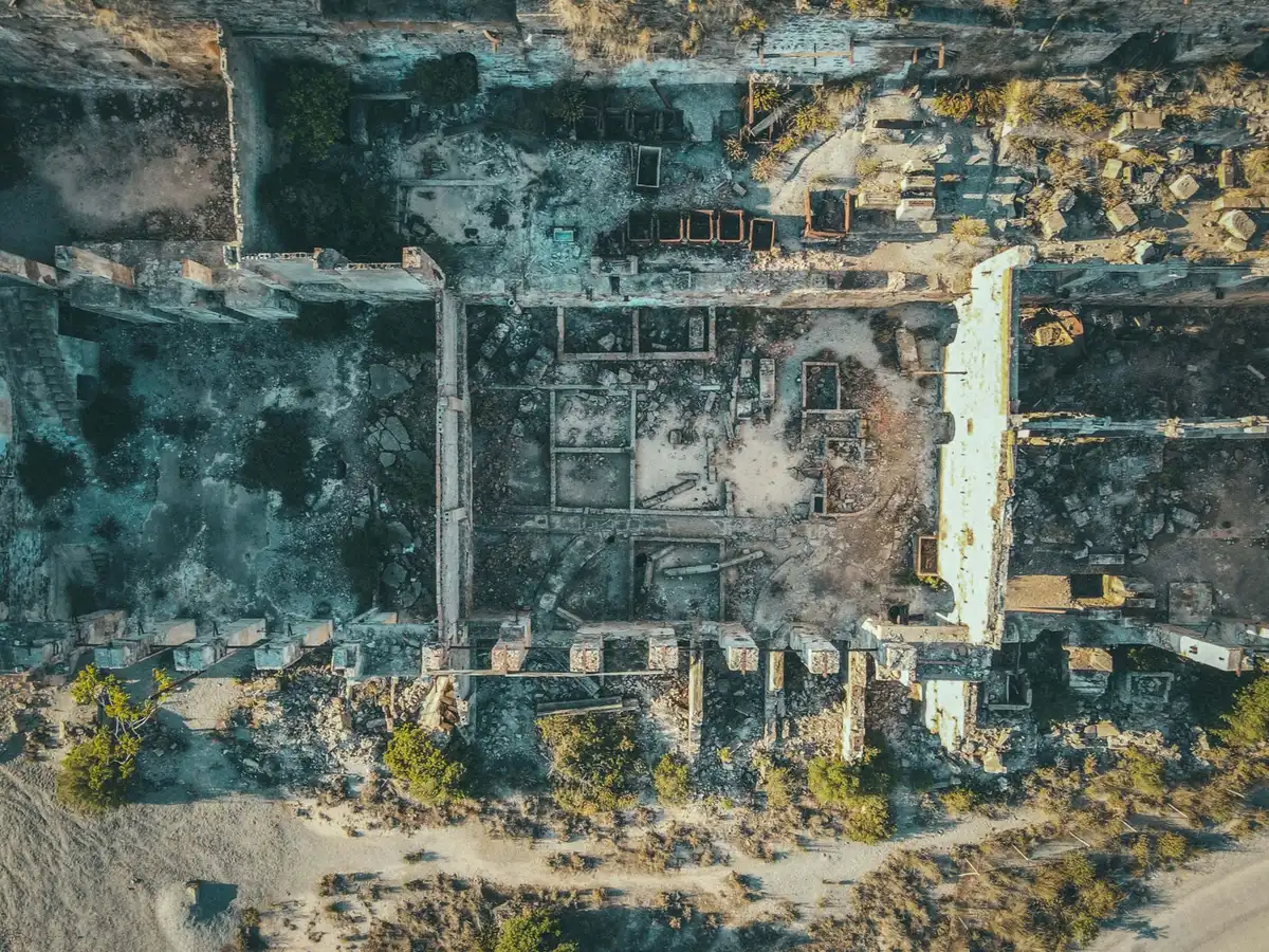 A destroyed cityscape reduced to rubble, green magical energy swirling above, a sense of devastation and cosmic power, anonymous figures in the distance