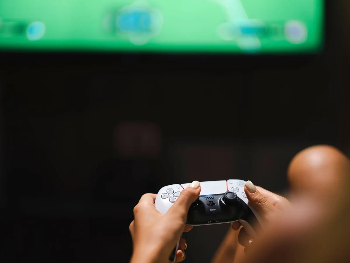 A sleek gaming console with glowing blue accents displayed against a dark background, representing cutting-edge graphics technology and AI-powered visual enhancement.