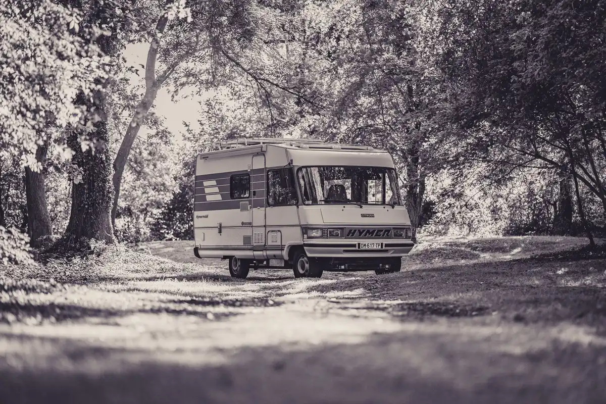 Intimate family camping scene with motorhome and rustic decor, soft evening light filtering through trees, a small child's toys visible, suggesting rural celebration atmosphere