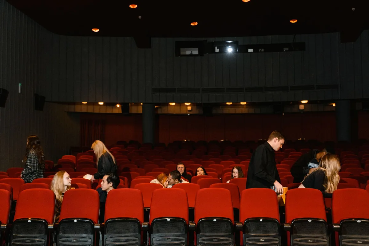 Cinema marquee and red carpet setup with elegant evening lighting, empty premiere venue waiting for guests, soft warm lights on the theater entrance, anticipation of an entertainment event