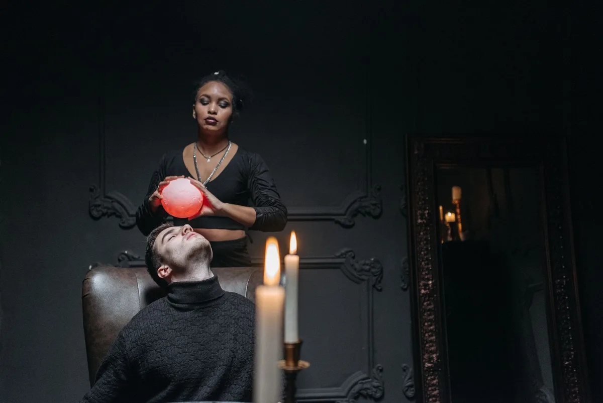 A vintage psychic's study with candlelight, tarot cards spread on a wooden table, crystal ball catching dim light, shadows playing across antique furniture, mysterious and timeless atmosphere