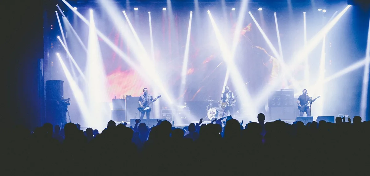 A stage spotlight illuminating an empty podium at a fan convention venue, dramatic shadows cast across rows of empty seats, anticipation in the air