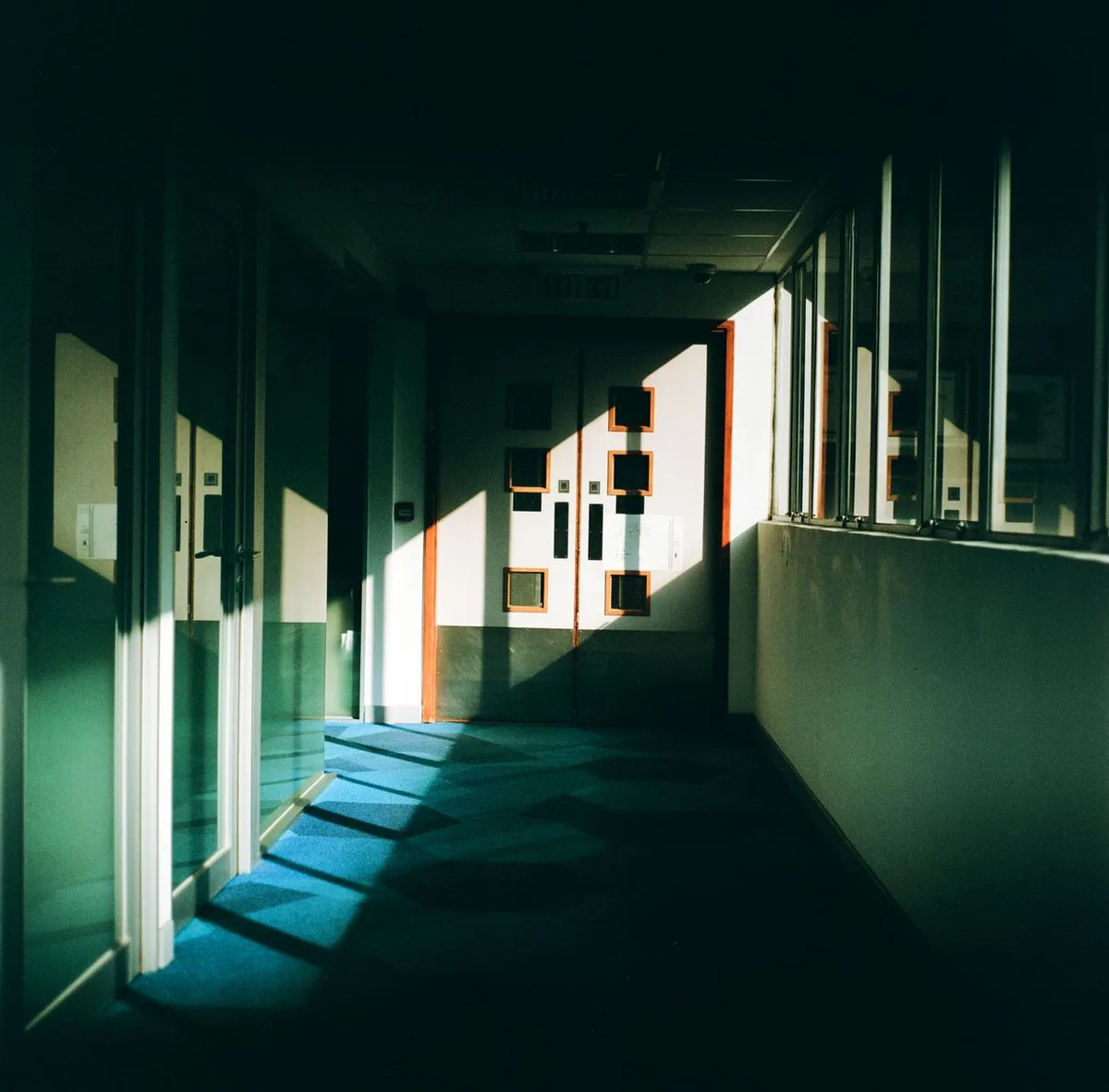 A split view showing a prison corridor with cells on one side and a courthouse hallway on the other, both empty and atmospheric, representing the dual worlds of law and crime