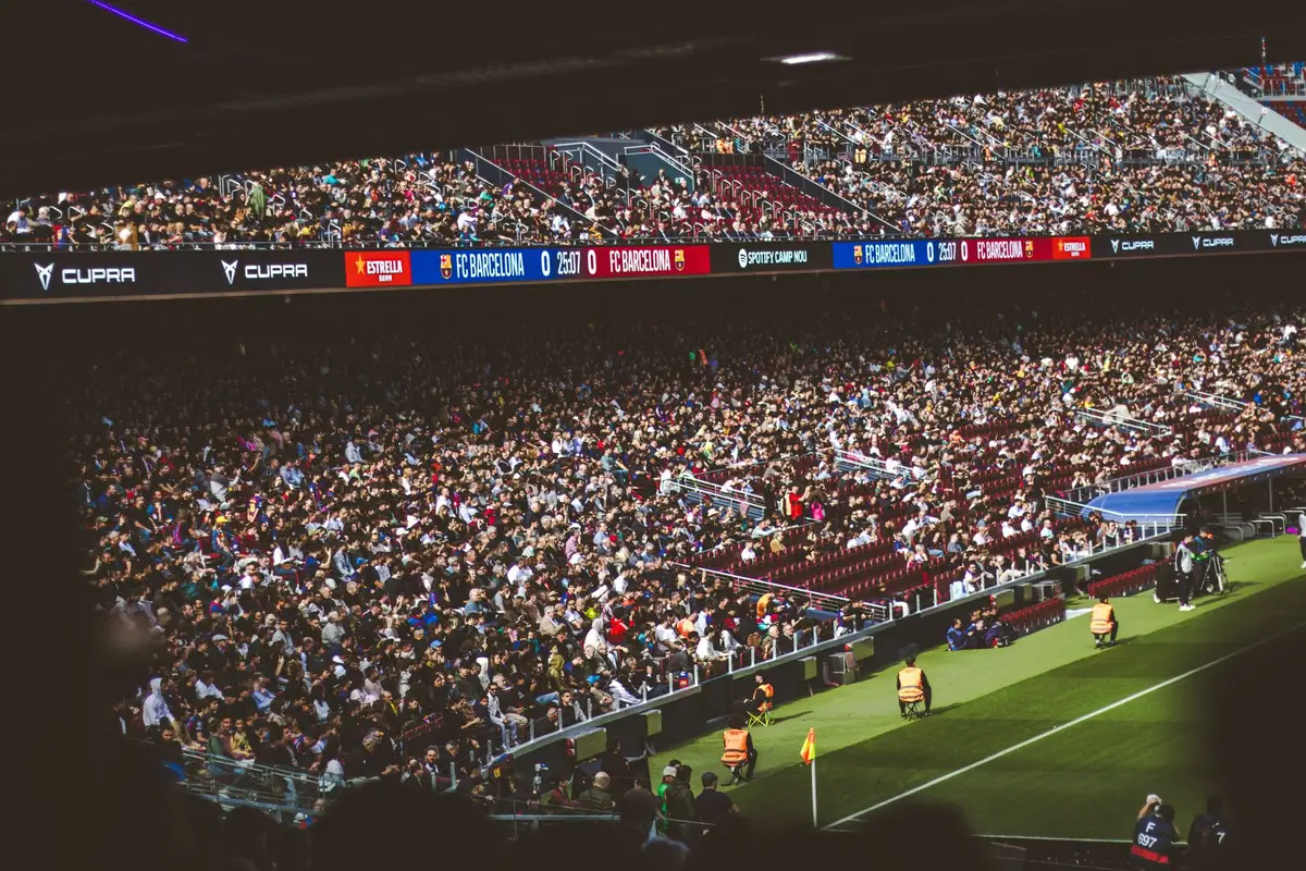 Estádio Santiago Bernabéu lotado com torcedores do Real Madrid celebrando durante o jogo, sob iluminação noturna, com os torcedores em pé aplaudindo