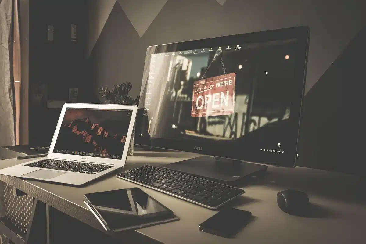 A silhouette of a game developer at a workstation with multiple monitors glowing with code and game assets, the figure backlit by blue light, papers and design sketches scattered across the desk, the atmosphere one of creation and innovation.
