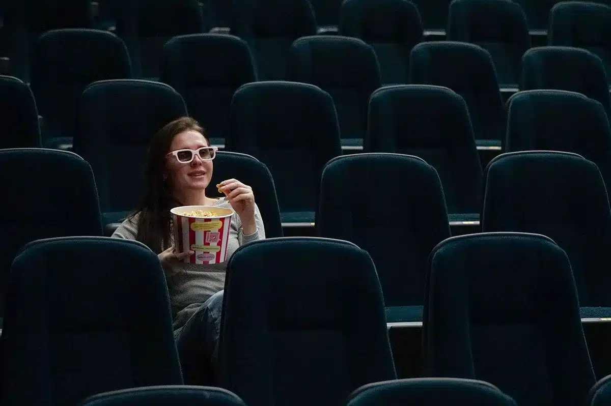 Empty cinema seats in rows, a single spotlight illuminating the screen in darkness, sense of anticipation and possibility