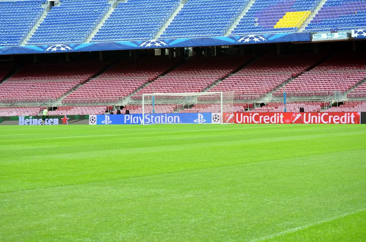 A stadium field with goal posts and empty stands under floodlights, ready for upcoming matches, with the grass freshly marked and bright