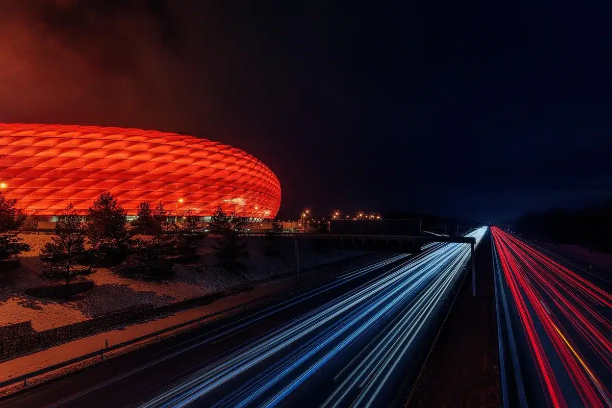 A packed stadium with floodlights illuminating the pitch at night, fans in the stands, the field ready for a match