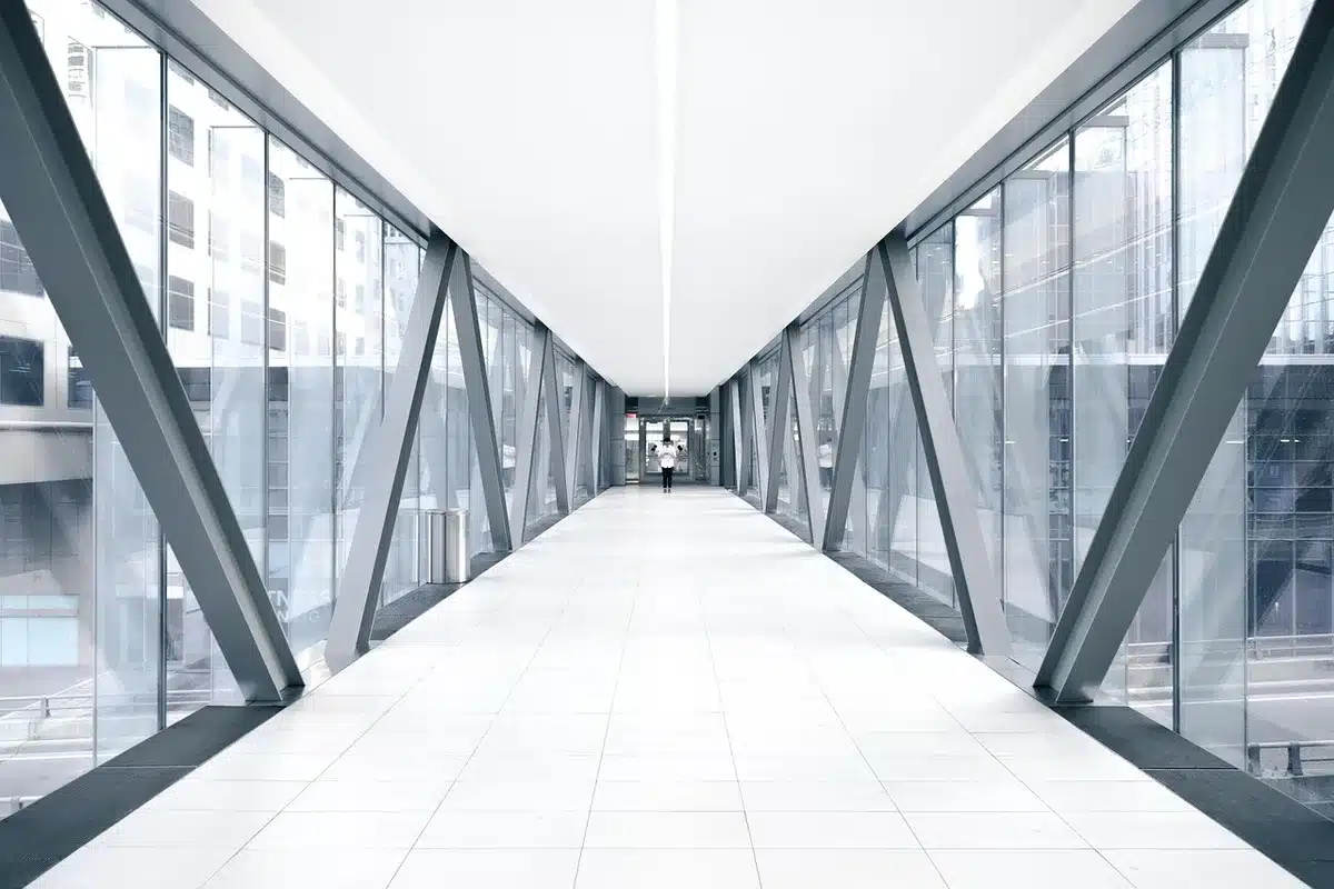 empty hospital corridor with a lone wheelchair under a cold overhead light, a folded blanket on the seat, hallway receding into soft focus