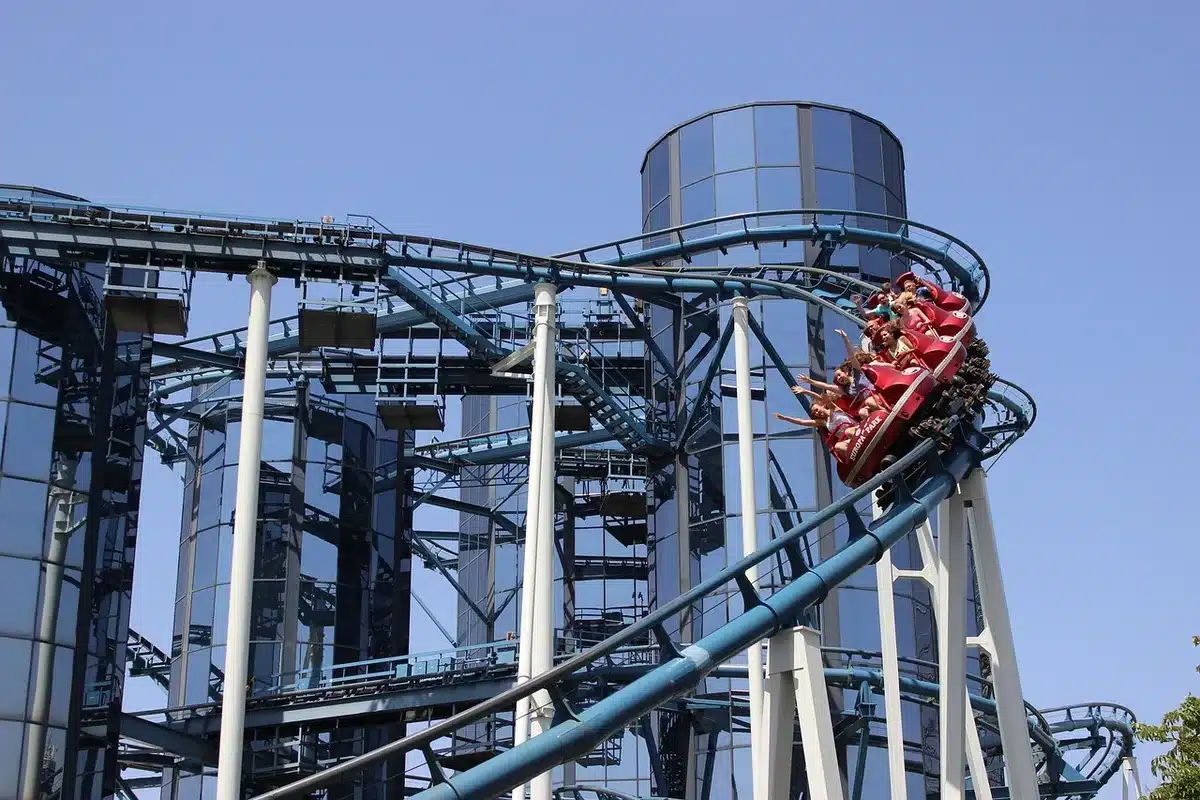 An empty roller coaster track curving sharply against a bright sky, with steel supports and multiple launch points visible, sunlight glinting off the rails, a sense of speed frozen in the structure