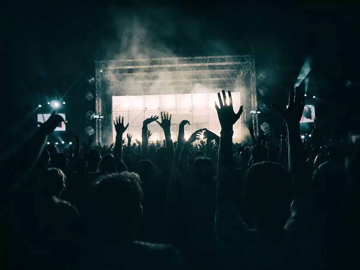 Empty festival stage with a single microphone and a backdrop bearing no logos, festival seating in soft focus