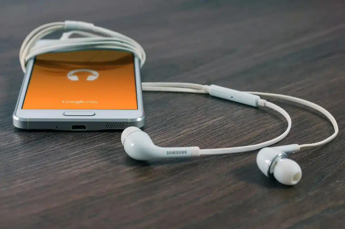 Anonymous hands holding smartphone showing a generic audio player, blurred city traffic behind