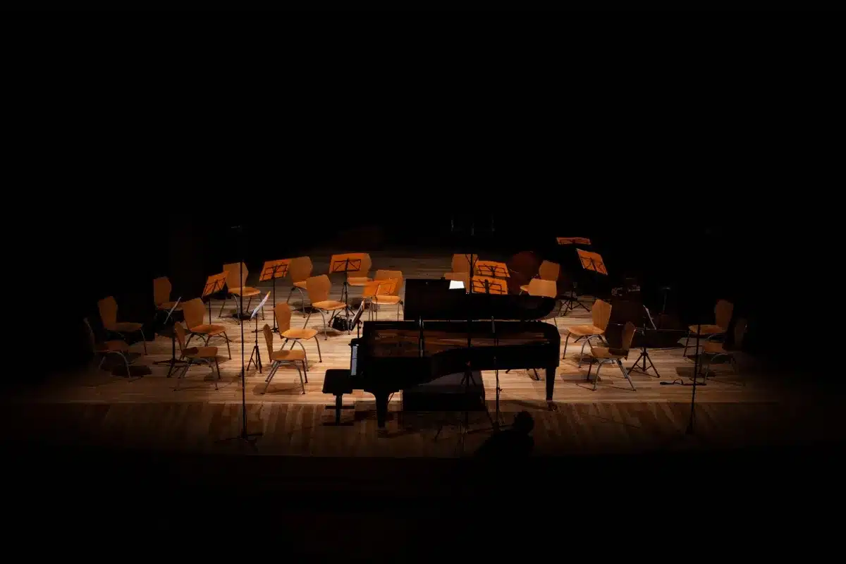 Empty Vivo Rio stage with a single spotlight on center, an acoustic guitar resting on a stand at stage front, no people visible