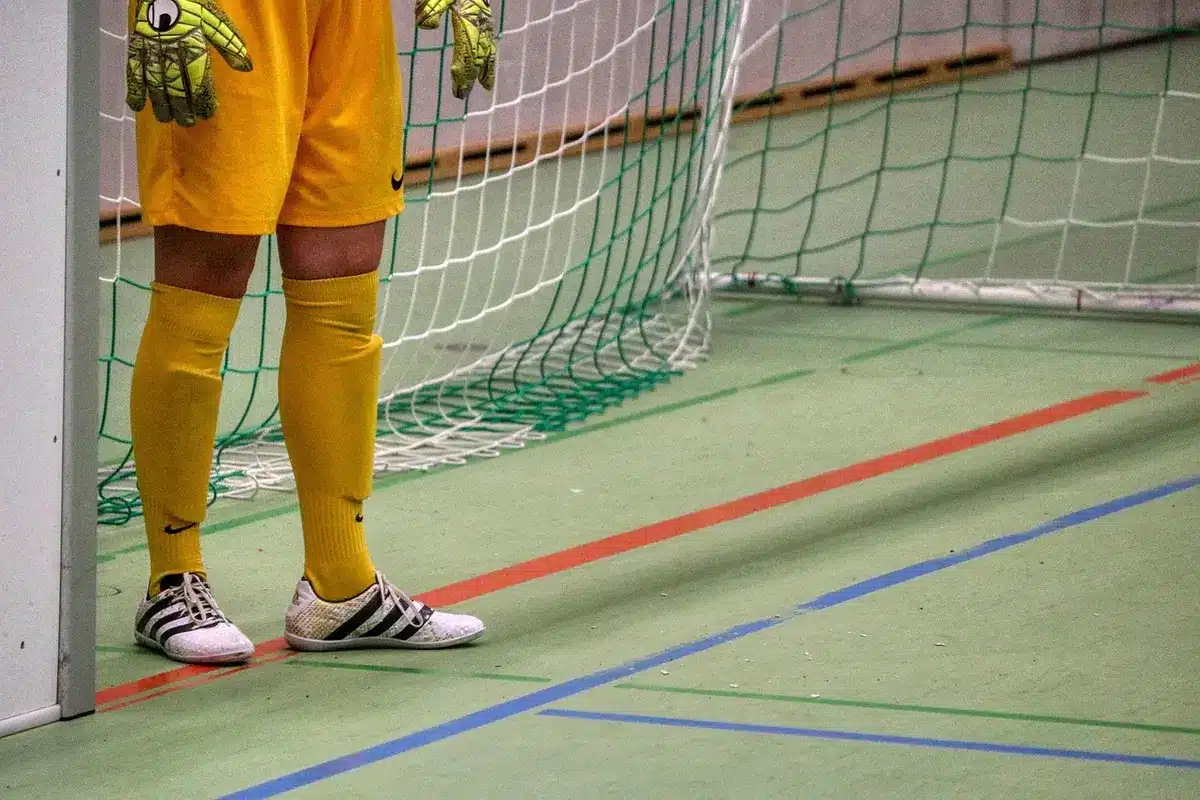 An anonymous goalkeeper diving across the goal line, arms extended, in a stadium under floodlights, desperation and final effort visible in the moment