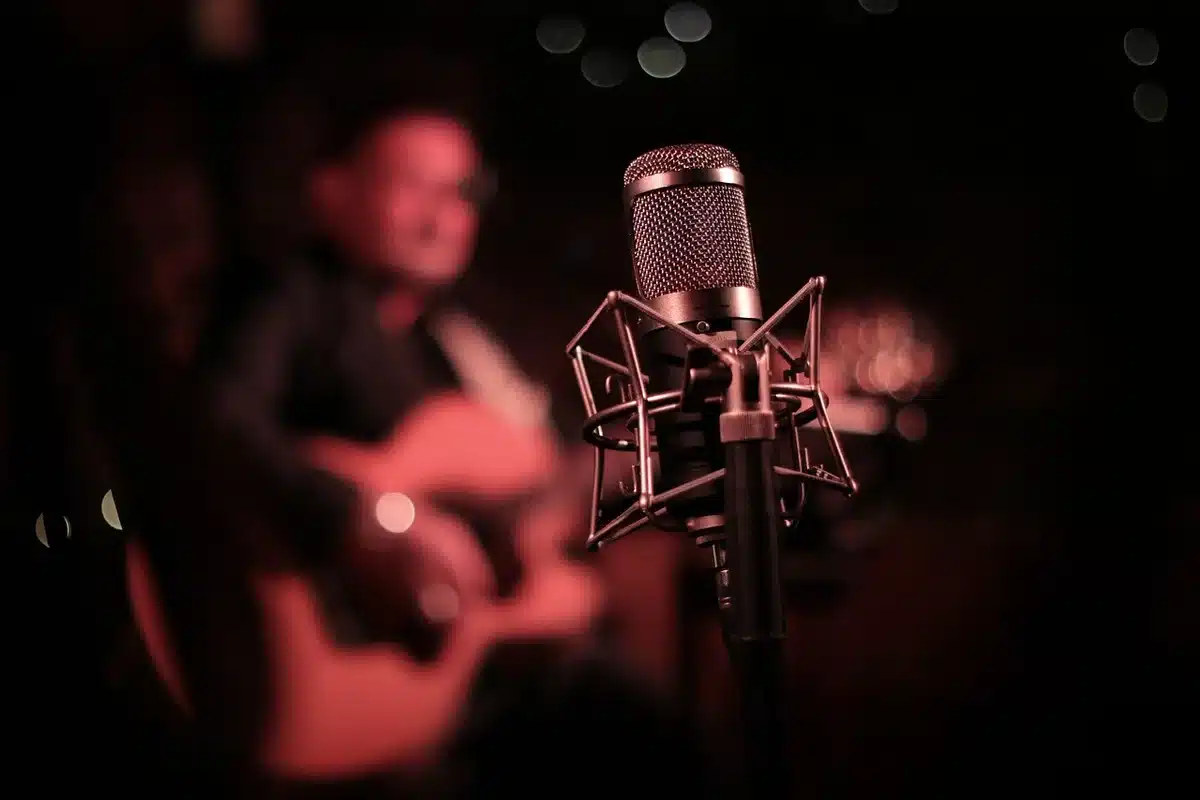 Anonymous close-up of a guitar on a stand beside a microphone, empty stage mood