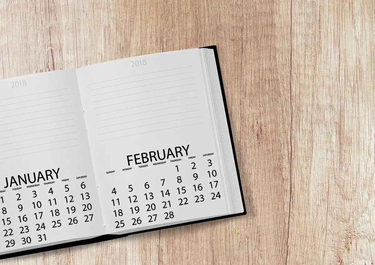 A symbolic desktop calendar opened to October 24 with no branding, a pen and an anonymous pair of reading glasses beside it, soft daylight on the page